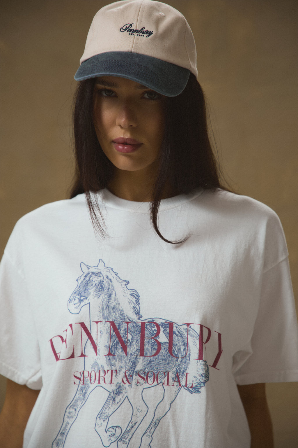 Model wearing Pennbury oat and blue embroidered tennis cap
