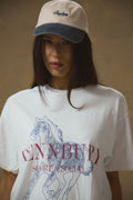 Model wearing Pennbury oat and blue embroidered tennis cap