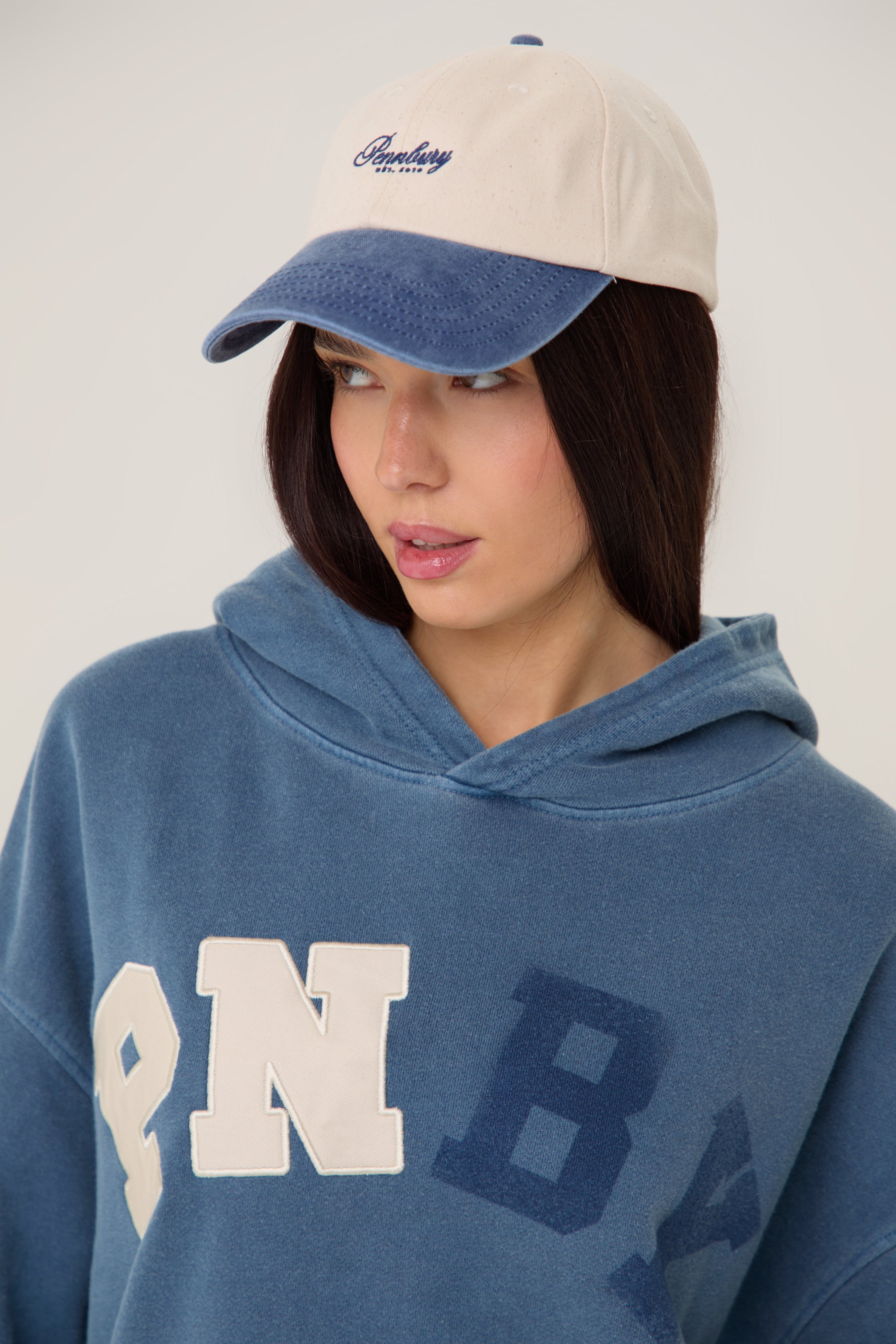Model wearing Pennbury oat and blue embroidered tennis cap