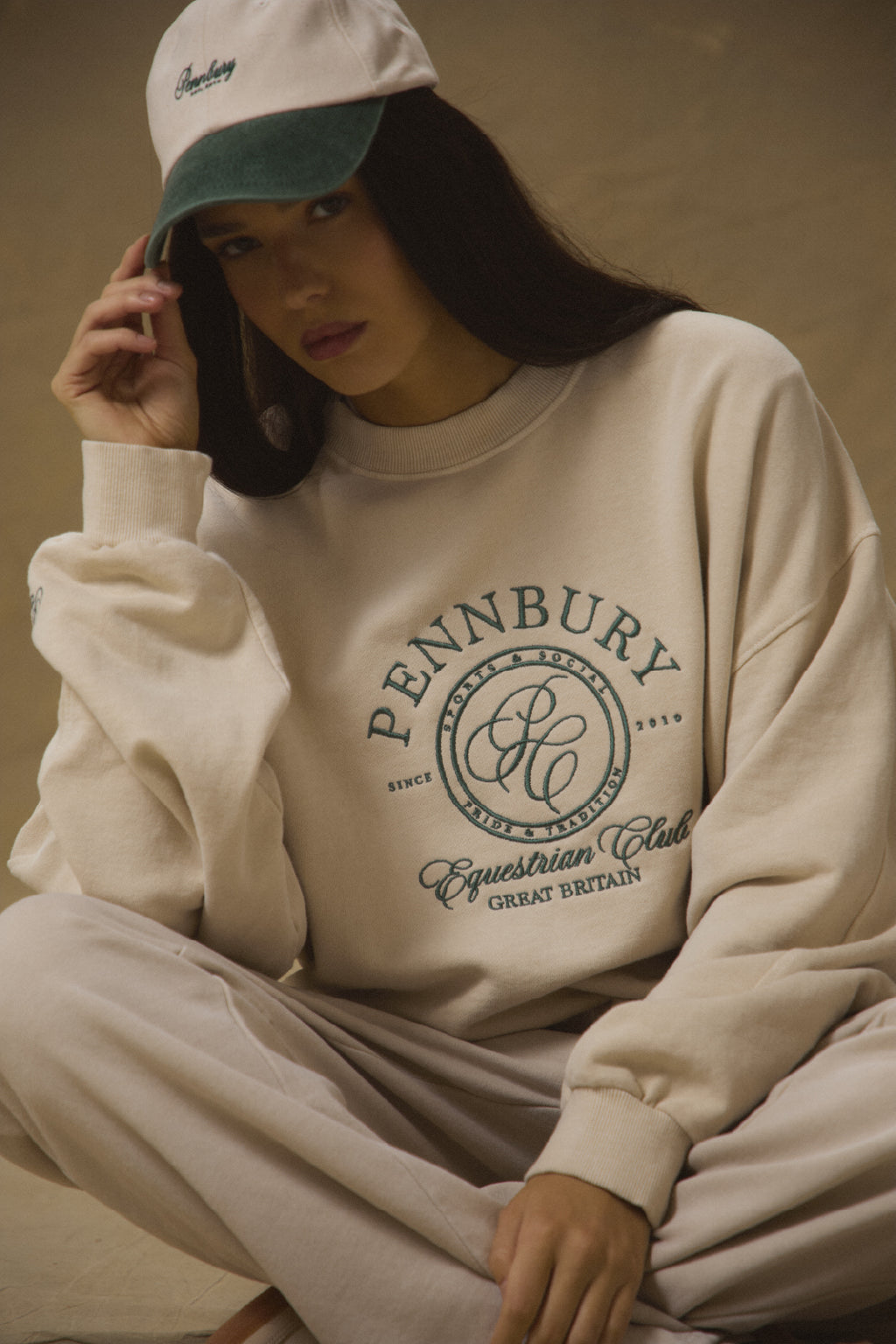Model wearing Pennbury oat and green embroidered tennis cap