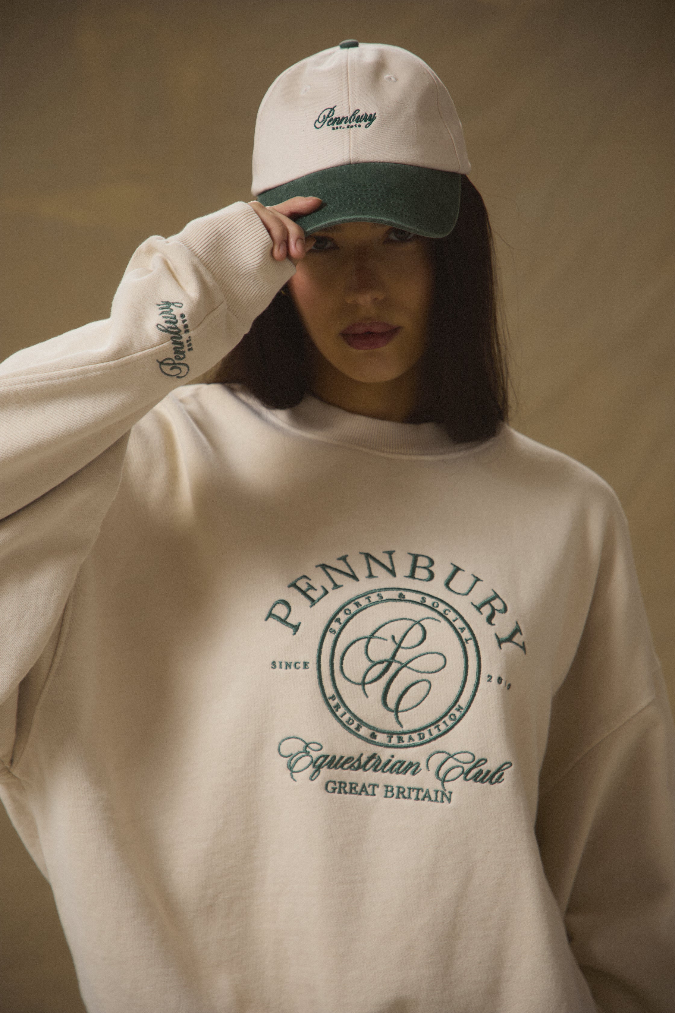 Model wearing Pennbury oat and green embroidered tennis cap