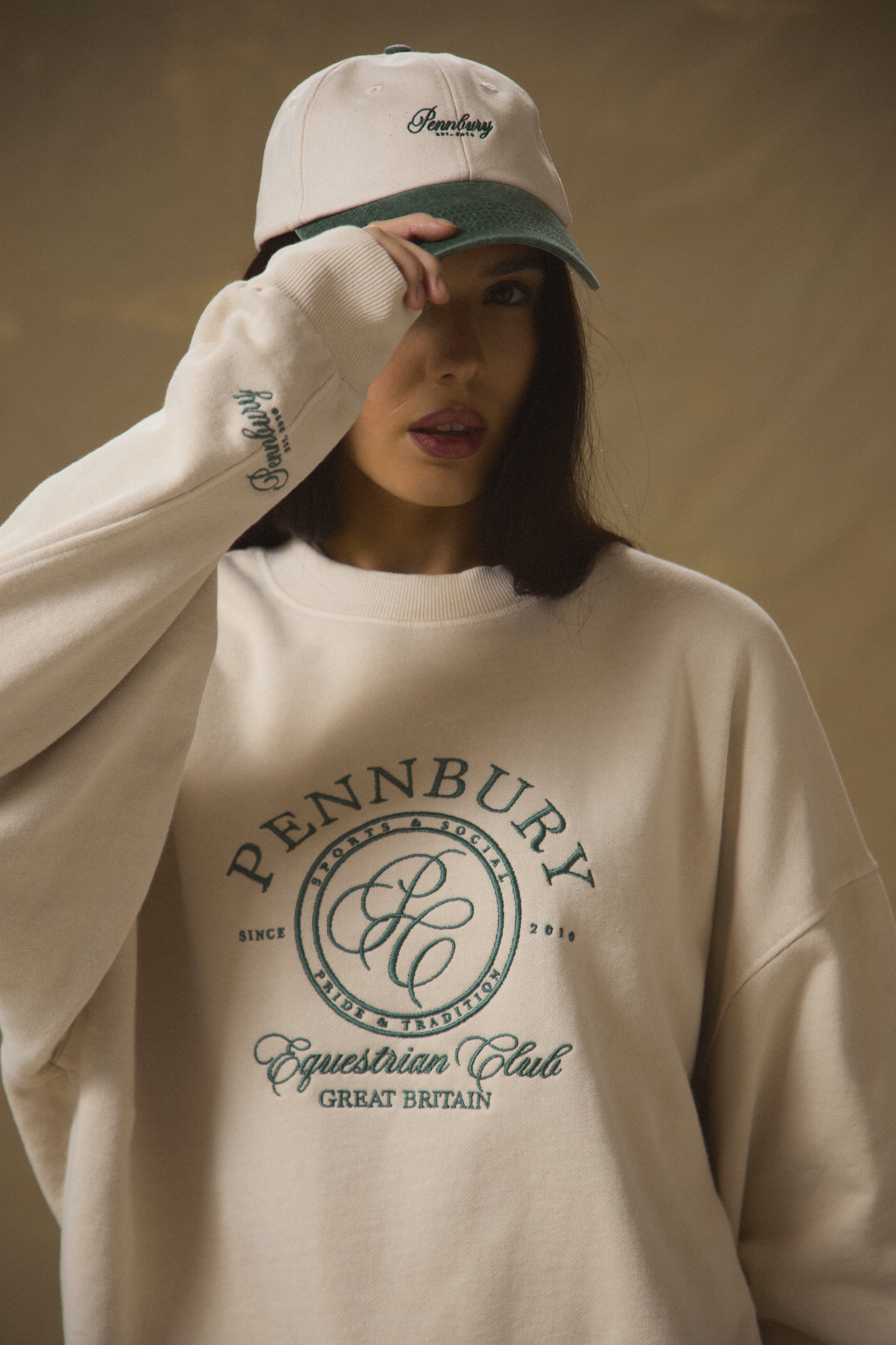 Model wearing Pennbury oat and green embroidered tennis cap 